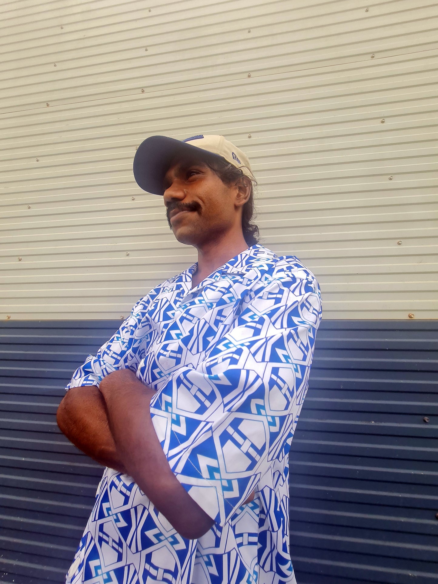 Man wearing a comfortable style button up shirt with the A-Frame print in the colour of Julah, the Rembarrnga word for water